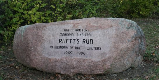 Boulder Sign reads Rhett walters memorial bike trail, Rhett's Run. In memory of Rhett Walters 1969 to 1996