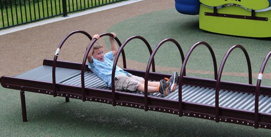 Boy navigating the rolling hoops at Woodridge Park Playground.