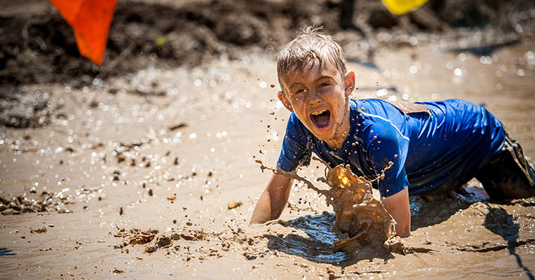 Splat: Mud-covered boy splashing in the water.