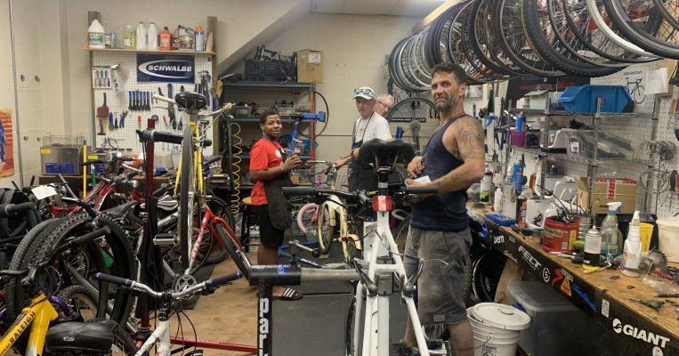 Two individuals receive service during walk-in repair at the Bike Co-op